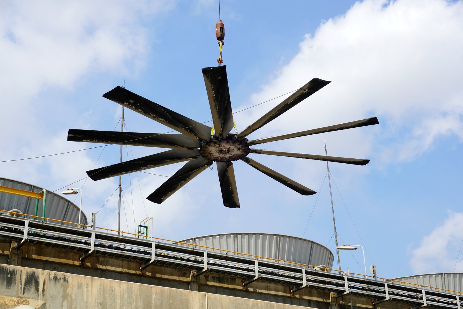 A multi blade axial fan assembly lifted out by crane above a cooling tower